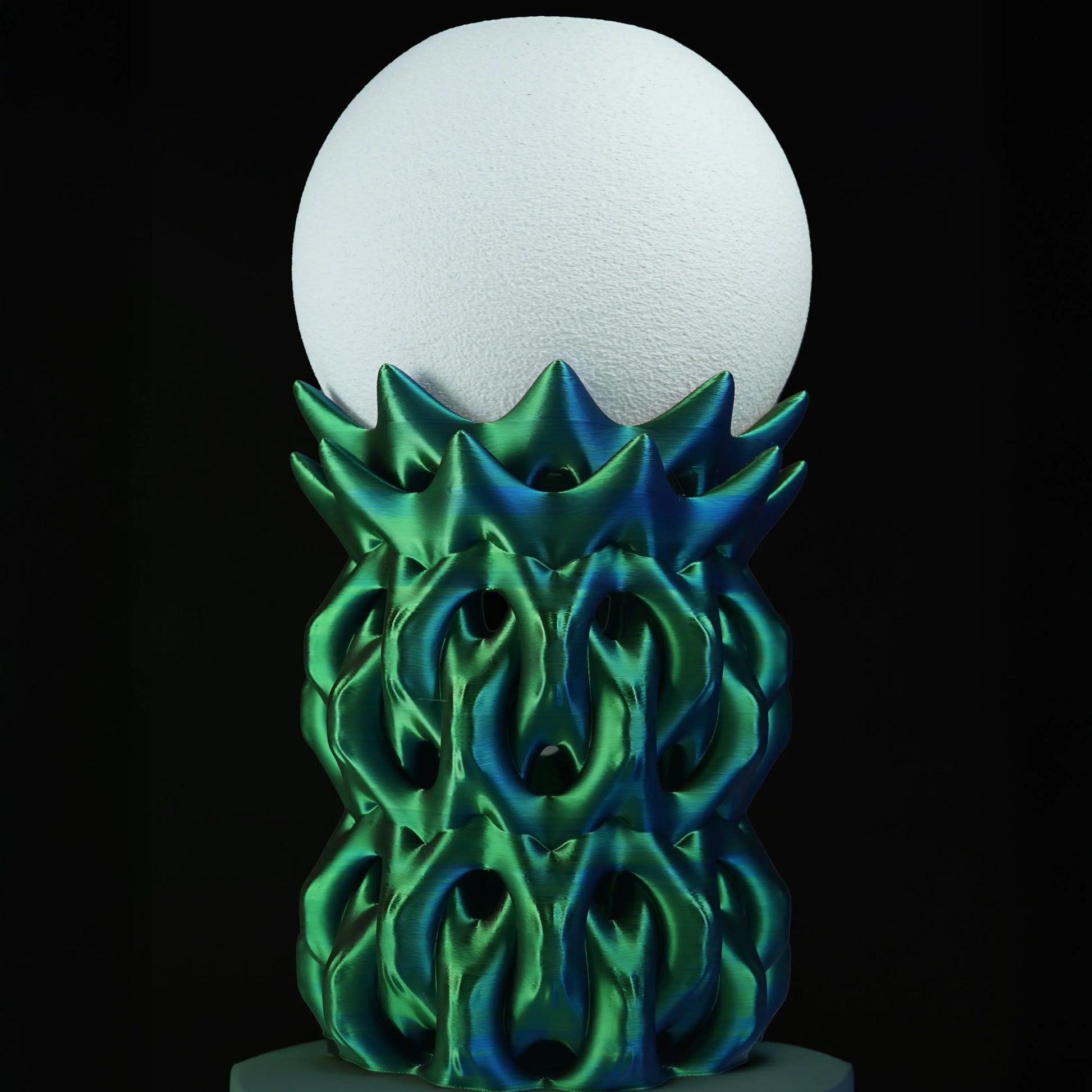 Decorative lamp with green flame-like design and white sphere on a black background
