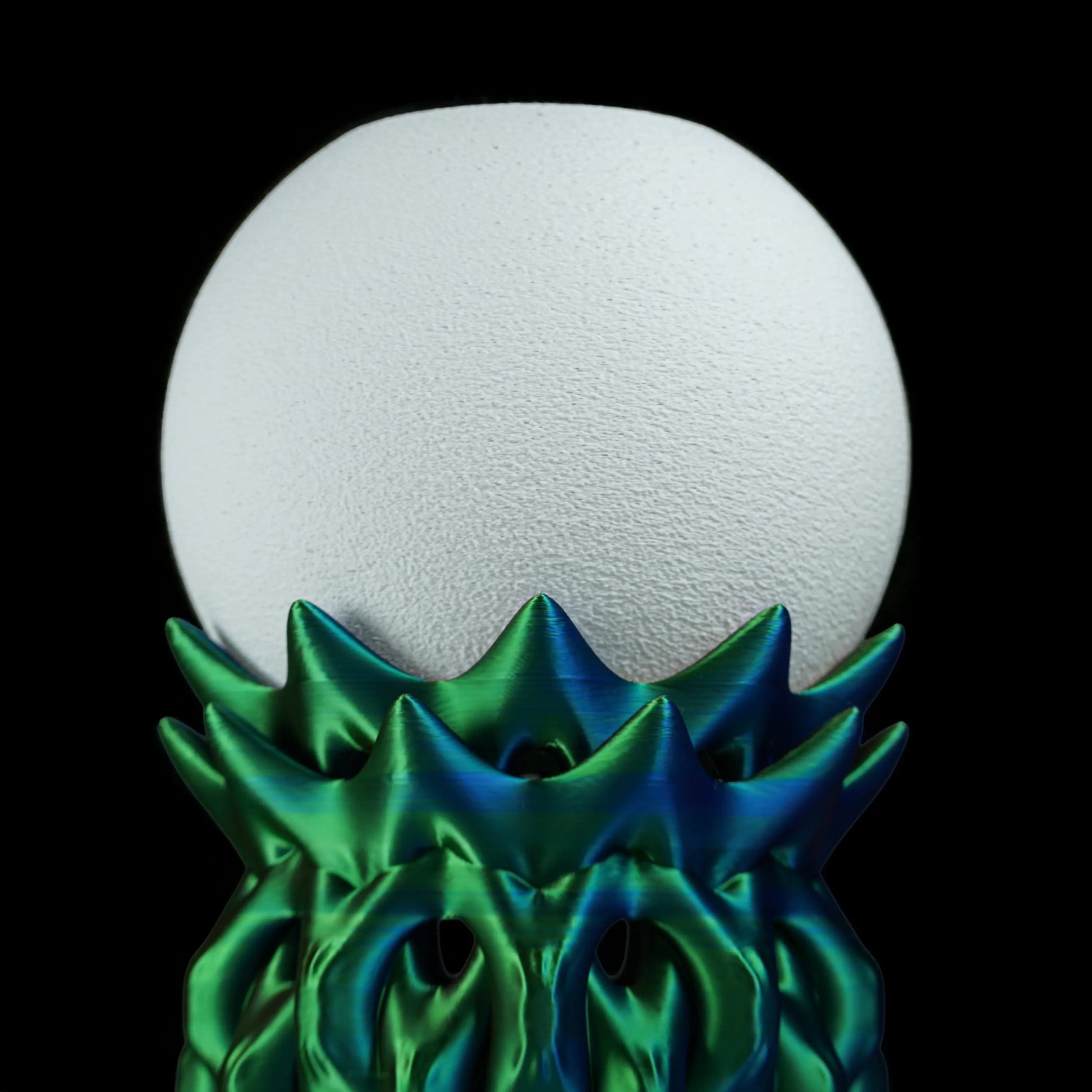 White sphere lampshade with green textured base on a black background
